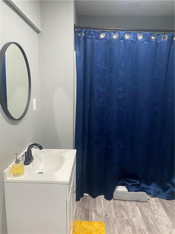 full bath with a shower with curtain, vanity, and wood finished floors