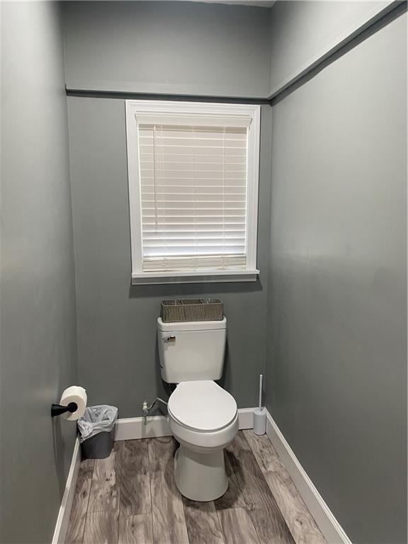 bathroom with baseboards, toilet, and wood finished floors