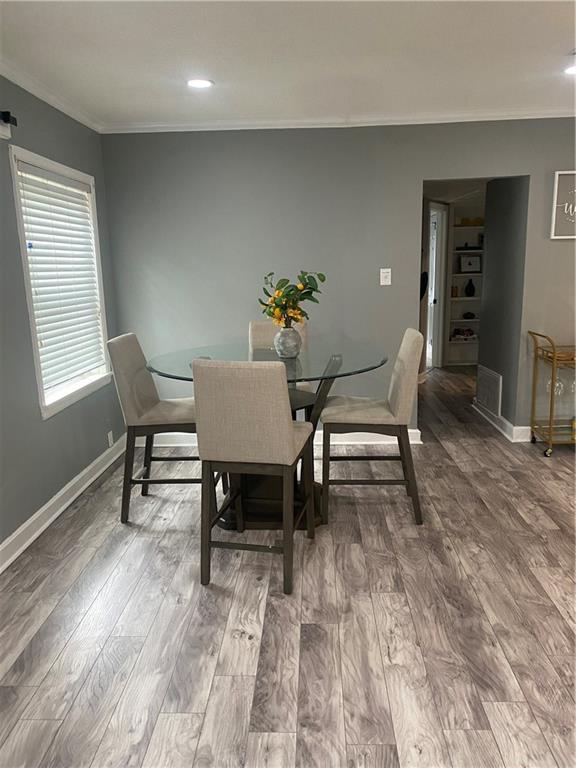 dining area featuring baseboards, wood finished floors, and crown molding