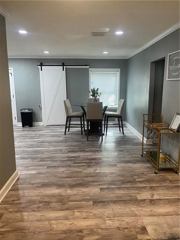 dining space featuring ornamental molding, a barn door, dark wood-style floors, and baseboards