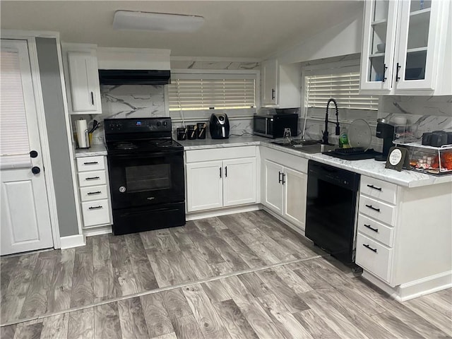 kitchen with tasteful backsplash, white cabinetry, light wood finished floors, and black appliances