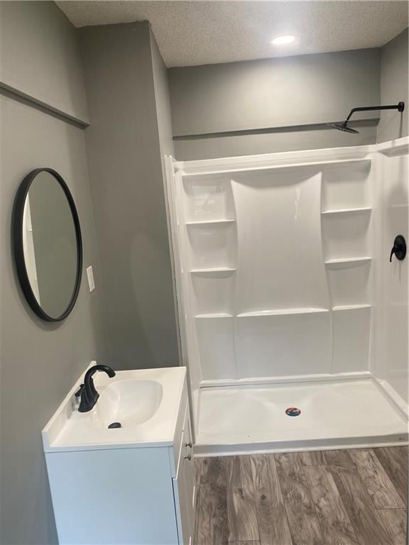 bathroom featuring vanity, a textured ceiling, a shower stall, and wood finished floors