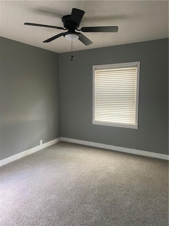 carpeted empty room with a ceiling fan, a textured ceiling, and baseboards