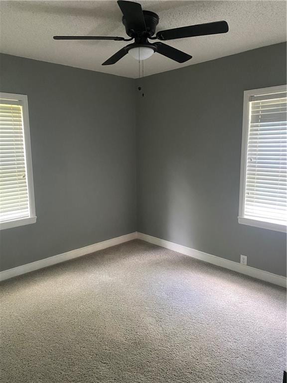 spare room with carpet, a textured ceiling, and baseboards