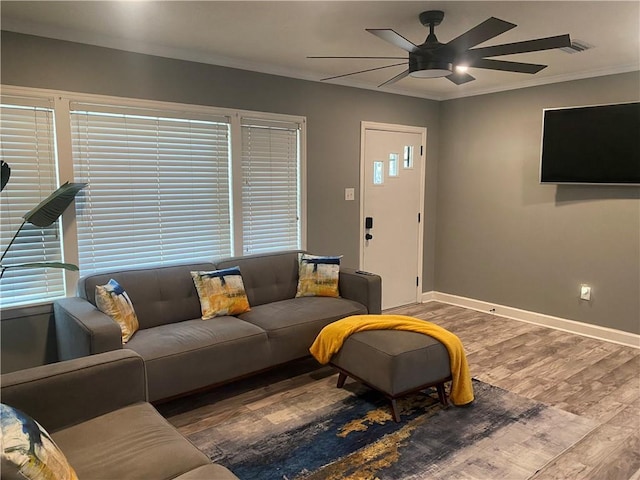 living room with a ceiling fan, baseboards, ornamental molding, and wood finished floors