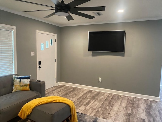 living room featuring baseboards, visible vents, ceiling fan, ornamental molding, and wood finished floors