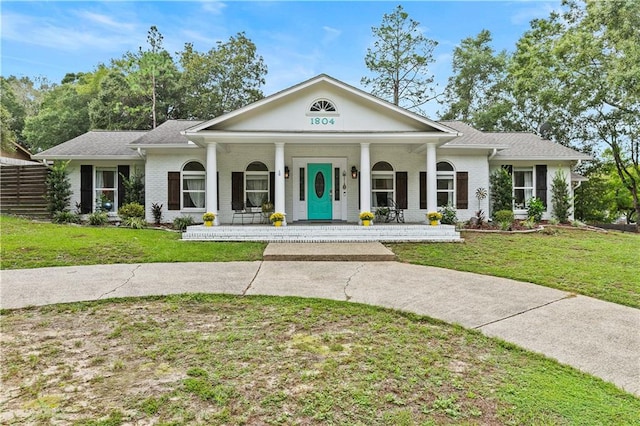 greek revival inspired property with a front yard and covered porch