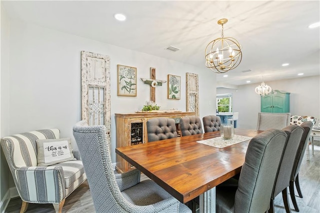 dining space with wood-type flooring and an inviting chandelier