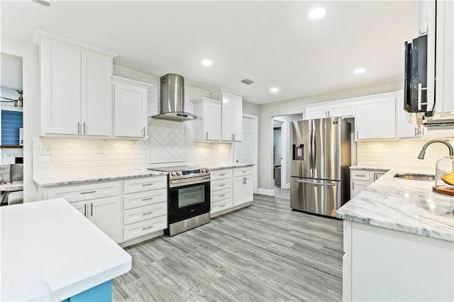 kitchen featuring white cabinets, sink, backsplash, wall chimney range hood, and stainless steel appliances