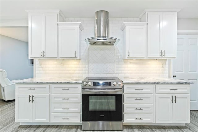 kitchen with stainless steel range with electric stovetop, wall chimney exhaust hood, backsplash, and white cabinetry