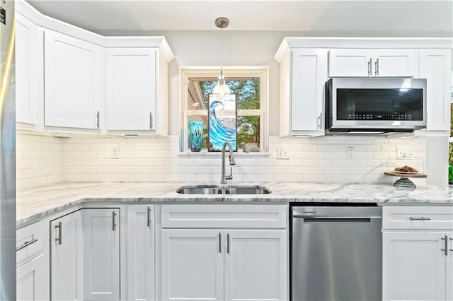 kitchen with decorative backsplash, white cabinetry, sink, and pendant lighting