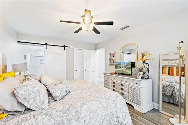 bedroom featuring ceiling fan, hardwood / wood-style flooring, and a barn door