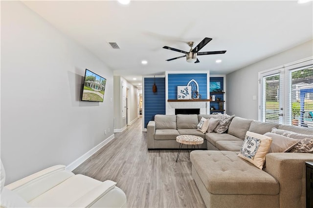 living room featuring light hardwood / wood-style flooring, ceiling fan, and a fireplace