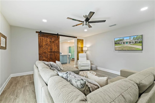 living room with light hardwood / wood-style floors, ceiling fan, and a barn door