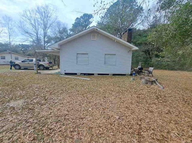 view of side of home with an attached carport and a chimney