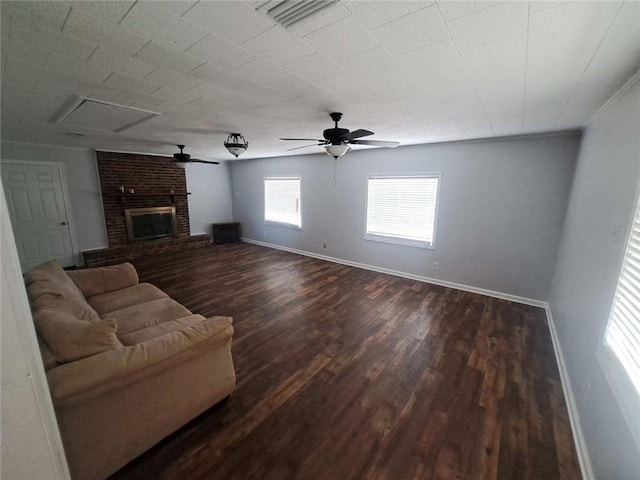 unfurnished living room featuring dark wood-style floors, ceiling fan, a fireplace, and baseboards