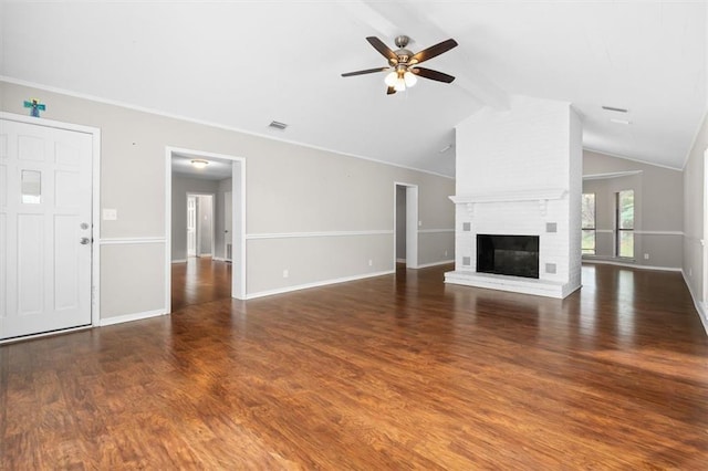 unfurnished living room featuring a brick fireplace, dark hardwood / wood-style flooring, ceiling fan, vaulted ceiling with beams, and ornamental molding