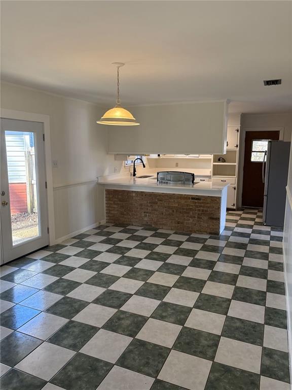 kitchen with kitchen peninsula, sink, pendant lighting, and fridge