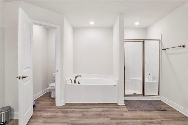 bathroom featuring hardwood / wood-style flooring, toilet, and separate shower and tub