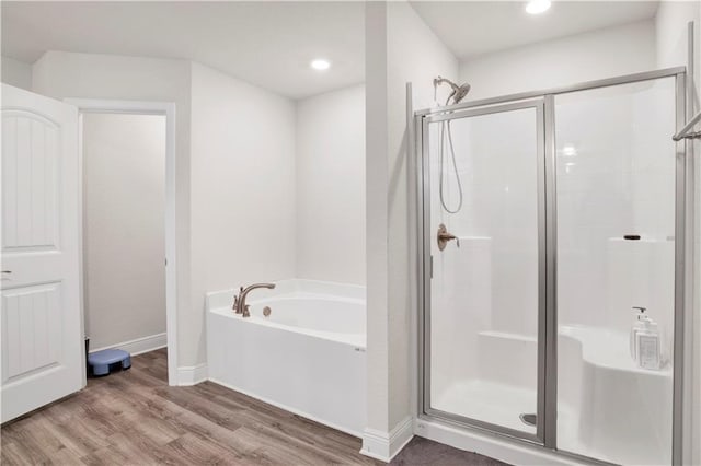 bathroom with hardwood / wood-style floors and shower with separate bathtub