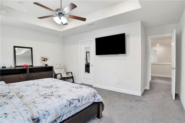 bedroom featuring light carpet, a tray ceiling, and ceiling fan