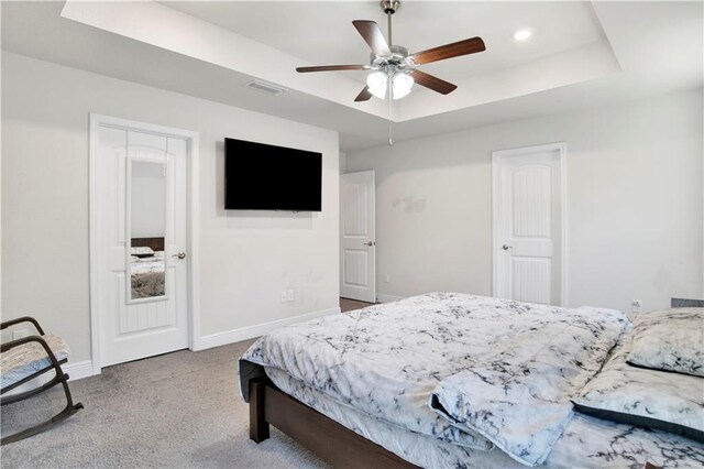 carpeted bedroom with a tray ceiling and ceiling fan