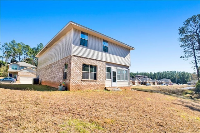 back of house featuring a yard, a garage, and central air condition unit