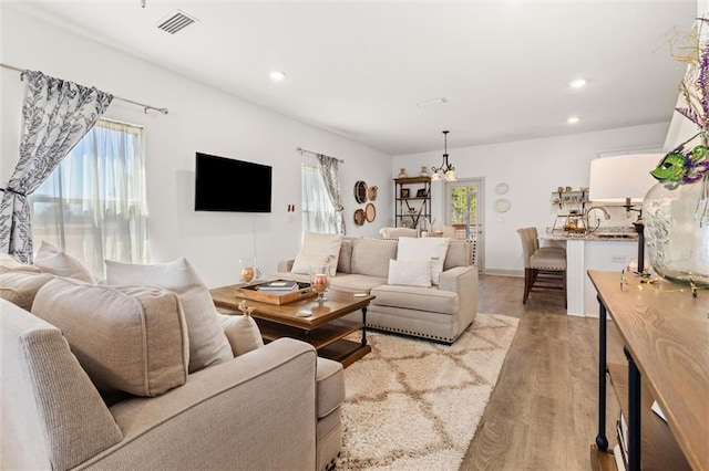 living area with a healthy amount of sunlight, light wood-type flooring, visible vents, and recessed lighting