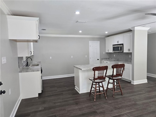2253 Downs Ct, Mobile, AL 36617 - kitchen featuring crown molding, decorative backsplash, baseboards, stainless steel microwave, and a sink