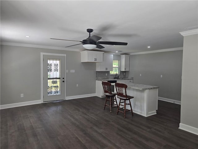 2253 Downs Ct, Mobile, AL 36617 - kitchen with a kitchen island, baseboards, ceiling fan, white cabinets, and a sink