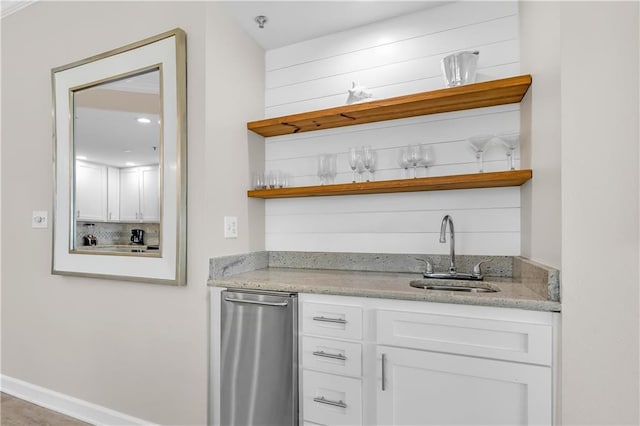 bar with wet bar, baseboards, and a sink