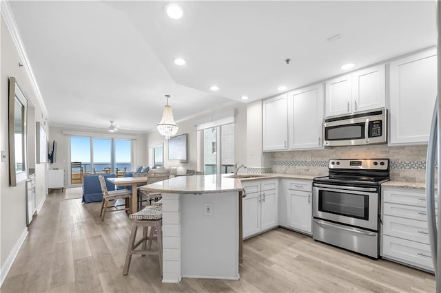 kitchen with backsplash, a peninsula, crown molding, and stainless steel appliances