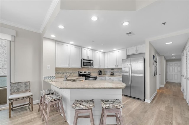 kitchen featuring crown molding, a sink, decorative backsplash, stainless steel appliances, and a peninsula
