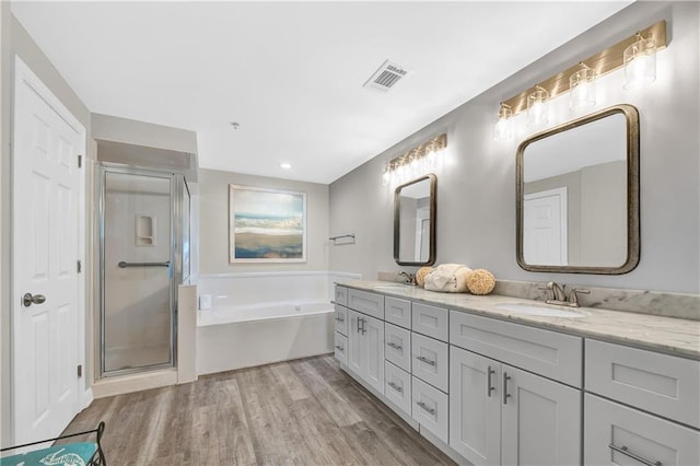 bathroom featuring a bath, wood finished floors, a sink, and double vanity