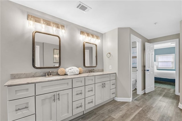 bathroom featuring double vanity, wood finished floors, visible vents, and a sink