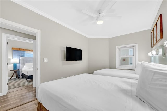 bedroom with light wood-style flooring, crown molding, baseboards, and ceiling fan