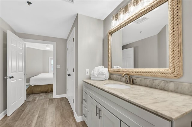 bathroom featuring baseboards, wood finished floors, visible vents, and vanity