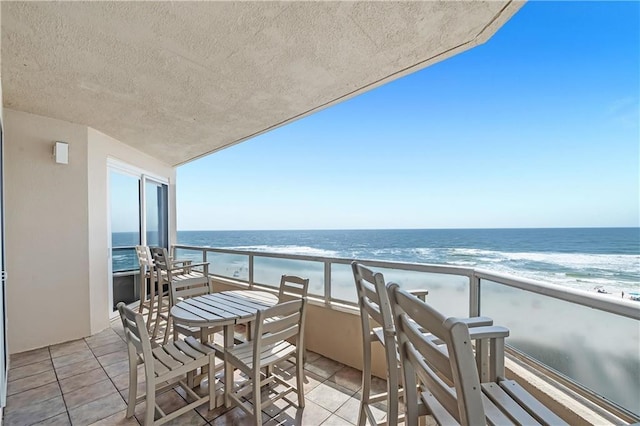 balcony featuring a view of the beach and a water view