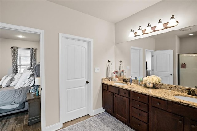 bathroom with baseboards, connected bathroom, a sink, and double vanity