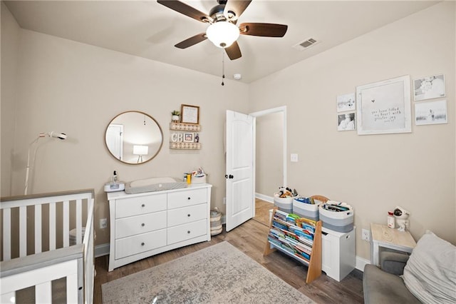 bedroom featuring a ceiling fan, wood finished floors, visible vents, and baseboards