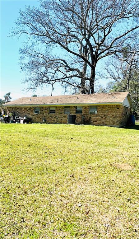 rear view of property featuring central AC and a yard