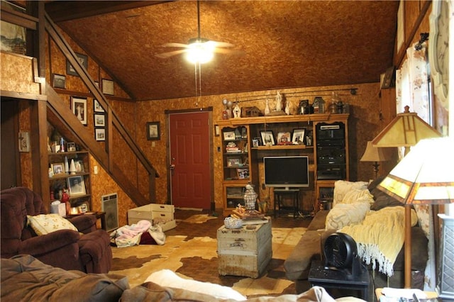 living area with lofted ceiling, stairs, and ceiling fan