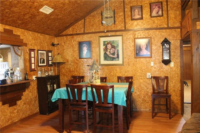 dining space featuring lofted ceiling, wood finished floors, and visible vents