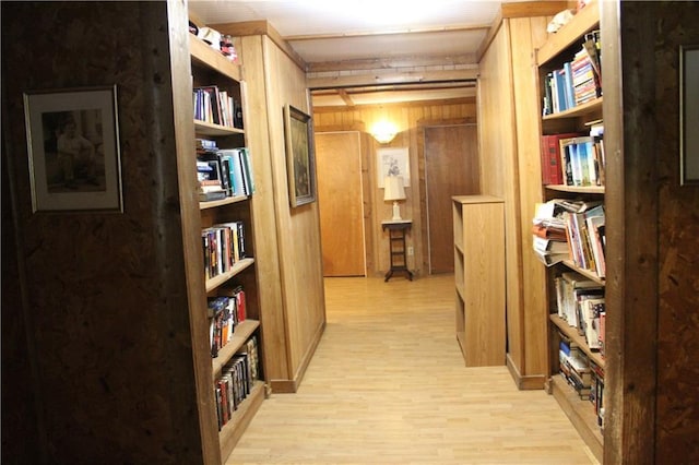 corridor with light wood-style flooring and wood walls