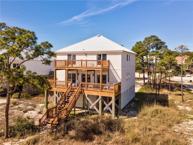 rear view of property with stairway, metal roof, a balcony, and a deck