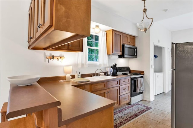 kitchen featuring sink, light tile patterned floors, decorative light fixtures, stainless steel appliances, and washer / clothes dryer