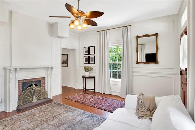 living room with dark hardwood / wood-style flooring, a brick fireplace, and ceiling fan