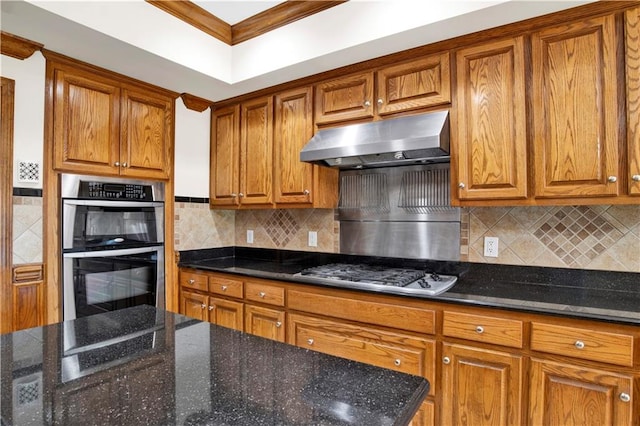 kitchen featuring crown molding, stainless steel appliances, decorative backsplash, and dark stone counters