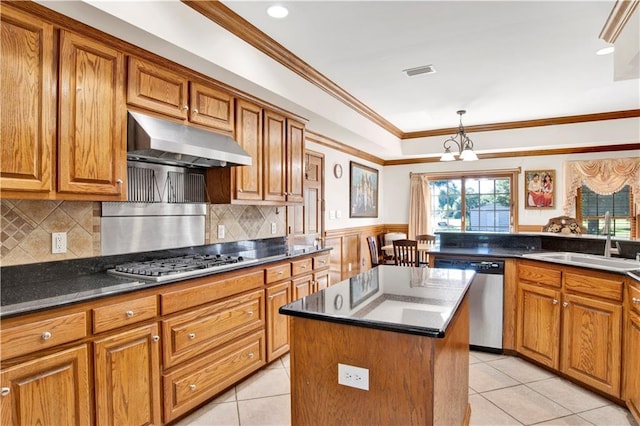 kitchen featuring light tile patterned floors, appliances with stainless steel finishes, a kitchen island, crown molding, and sink