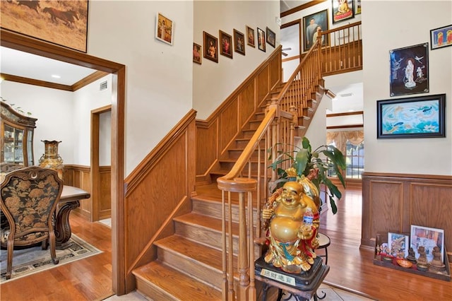 staircase with ornamental molding, hardwood / wood-style floors, and a high ceiling